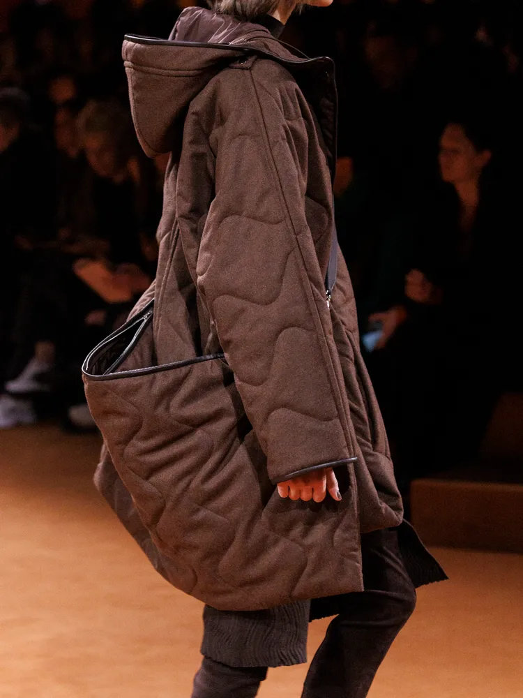 表面飾有絎縫細節的斜背大包，為整體注入戶外運動的元素。品牌提供