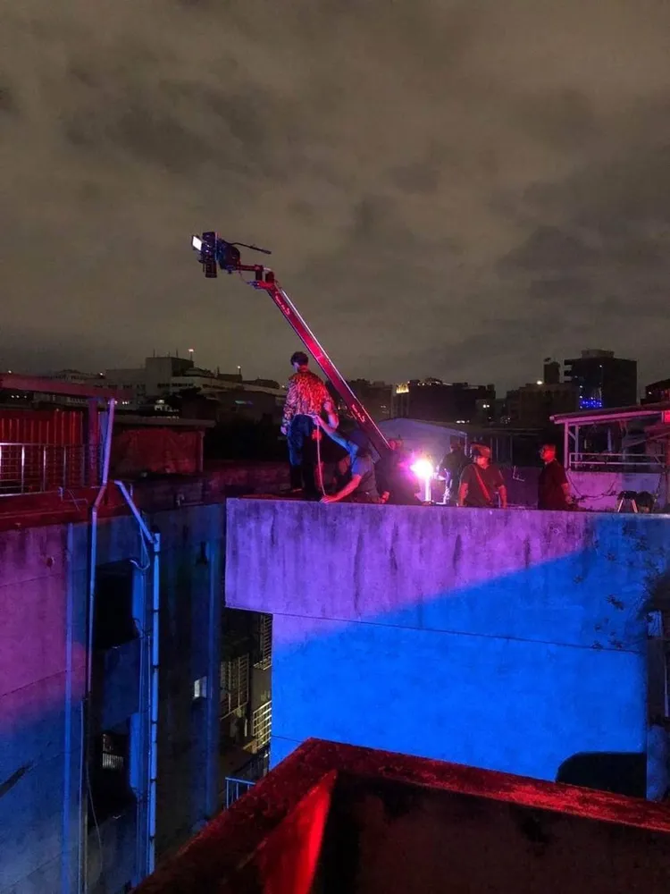 炎亞綸站在頂樓牆邊賣命演出，沒有堅固的防護設備。翻攝台灣迷因臉書