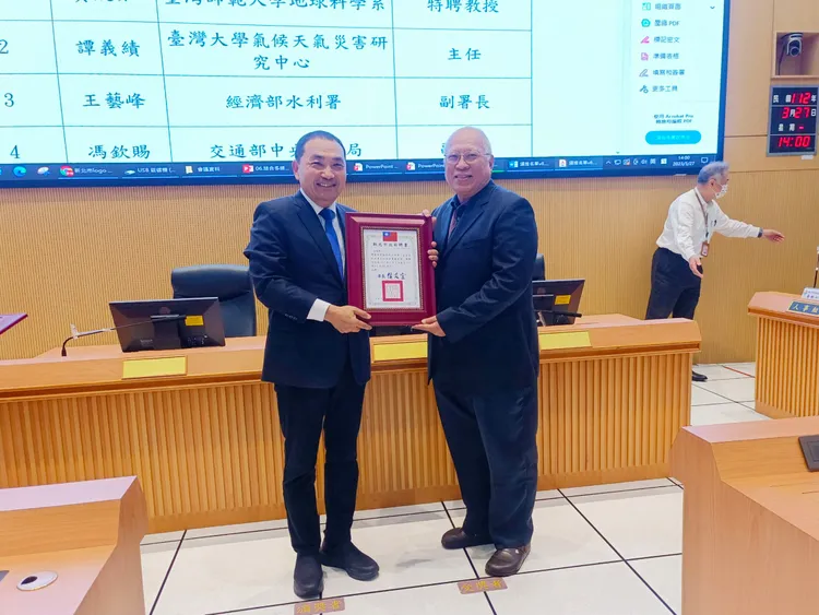 新北市長侯友宜授頒聘書給臺灣大學氣侯天氣災害研究中心主任譚義績。消防局提供