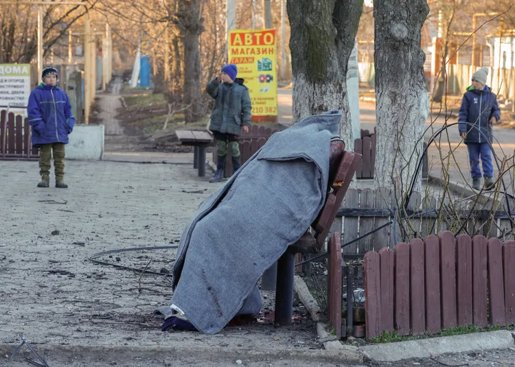 頓內次克小鎮沃爾諾瓦哈（Volnovakha）13日遭俄軍砲襲，一名兒童停下腳步，看著街上坐在公園椅上的遺體。路透社