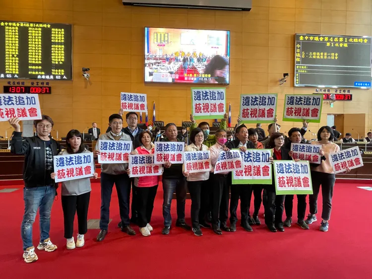 民進黨市議員日前在臨時會舉牌抗議市府編列購物節3.5億元追加預算，最後全案退回。資料照片