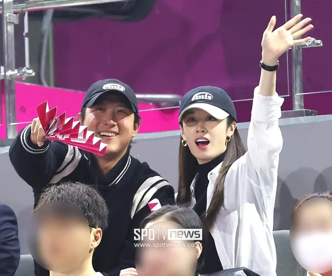 芝妍（右）升格幸福人妻，與老公黃載均看球賽，開心對著鏡頭揮手。翻攝SPOTV news