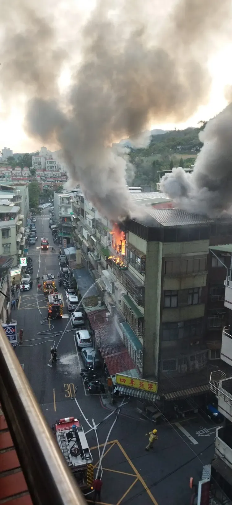 公寓頂樓竄出大量濃煙，警消拉設水線搶救。翻攝臉書《信義區三兩事》