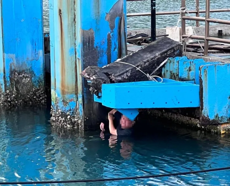 許男抓著輪胎等待救援。讀者提供