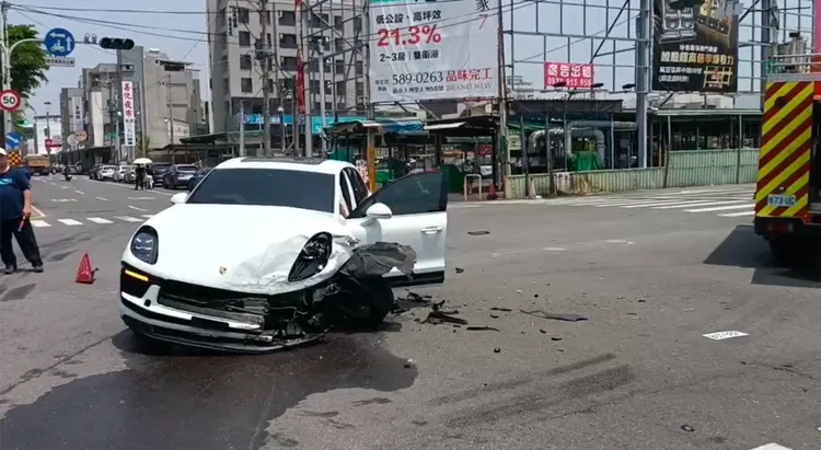 白色保時捷遭撞後，左側車頭毀損，連車輪都歪掉。讀者提供