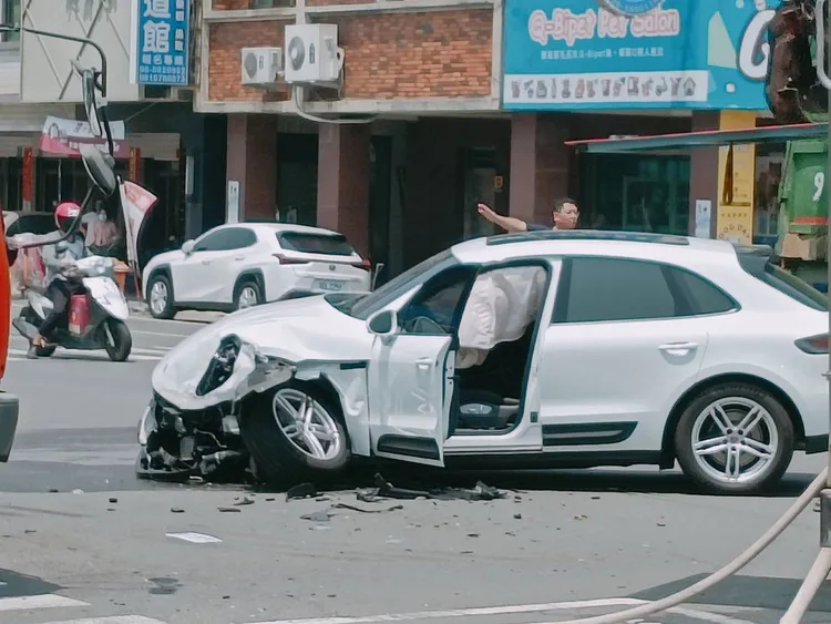 白色保時捷遭撞後，左側車頭毀損，連車輪都歪掉。讀者提供