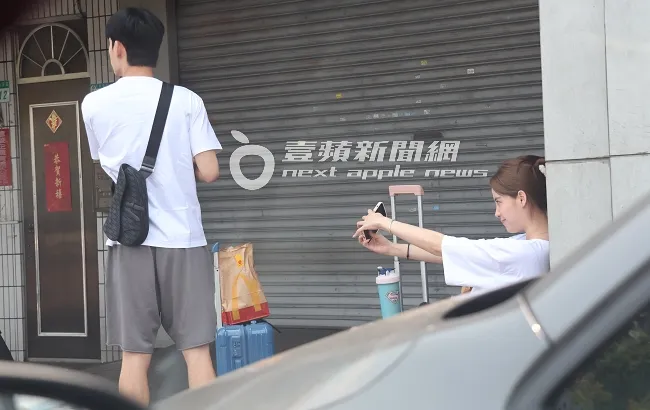 歐陽妮妮（右）在車行門口等車，開心舉起手機大玩自拍美照，心情看來開心。特勤中心攝