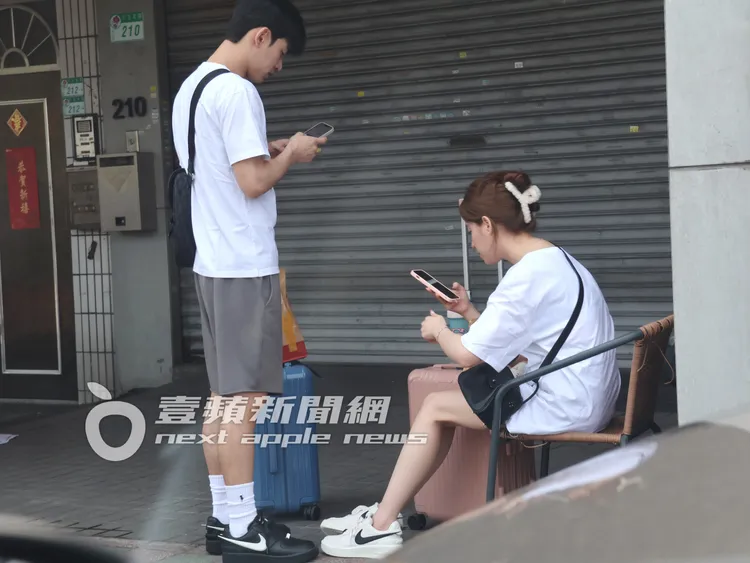 歐陽妮妮（右）與張書豪穿情侶鞋，各自看手機等洗車行開門。特勤中心攝