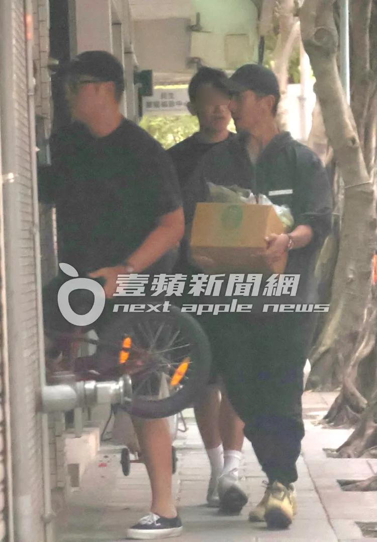 張孝全（左）拿著腳踏車，修杰楷則抱著一箱食材跟在後面準備上樓。特勤中心攝