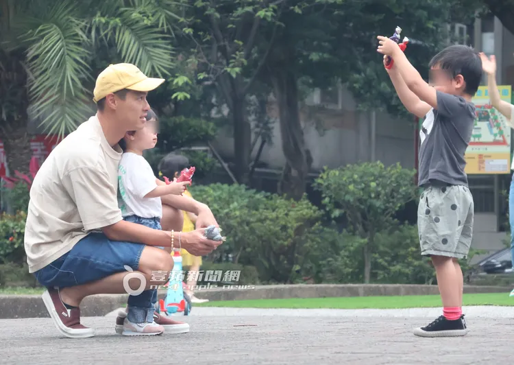 楊祐寧（左）一邊抱著女兒一手拿著恐龍玩具，與張孝全兒子手上的超人力霸王玩具互相玩耍。特勤中心攝