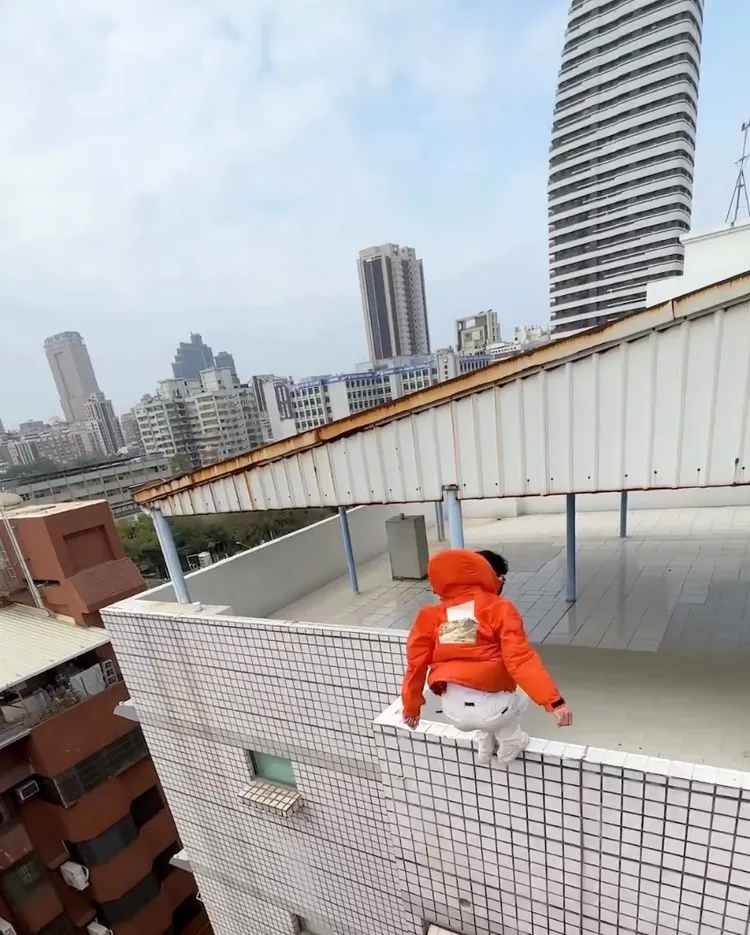 紅衣男成功跳到對面大樓的女兒牆上。翻攝畫面