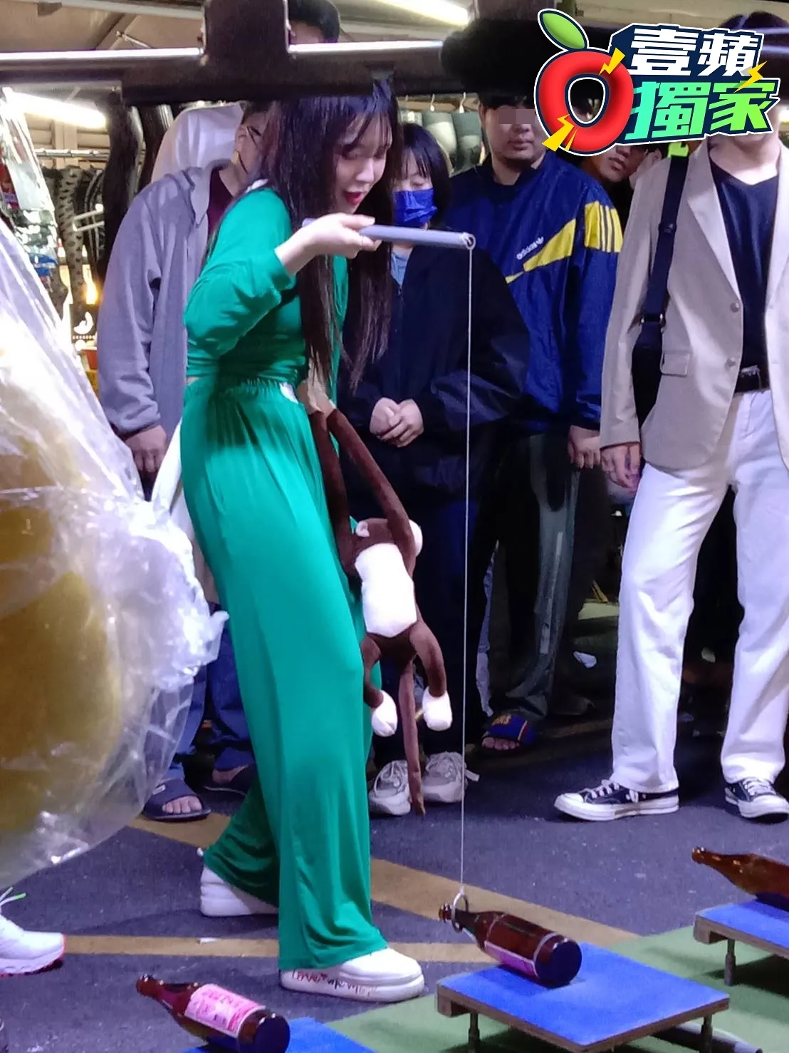 身材曼妙的韓星李多慧,火辣逛中壢夜市,認真玩「立酒瓶」遊戲,將猴子玩偶獎品掛在包包上,模樣十分可愛。讀者提供