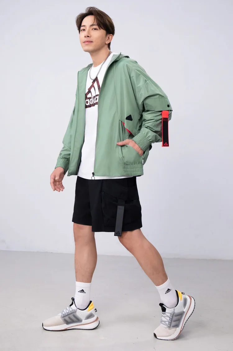 adidas形象大使坤達穿著adidas City Escape系列連帽防風外套，搭配Logo T恤、黑色平織運動短褲，展現兼具運動及時尚的戶外休閒風貌。品牌提供