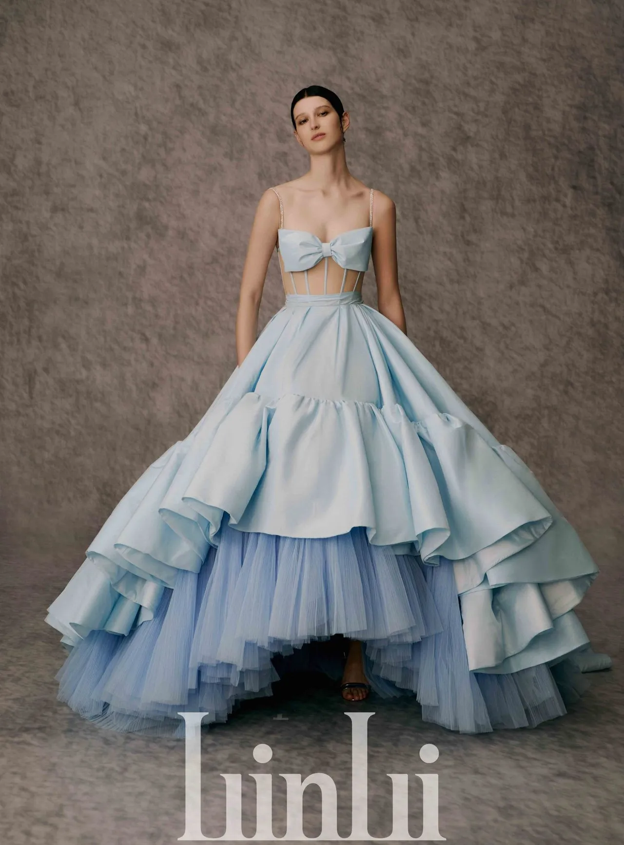 白标系列天蓝塔夫塔绸荷叶礼服，采平口细肩带领型搭配前短后拖摆大A字裙设计，透肤马甲上身使用大蝴蝶结作为罩杯的俏皮造型，性感又带点趣味。 品牌提供