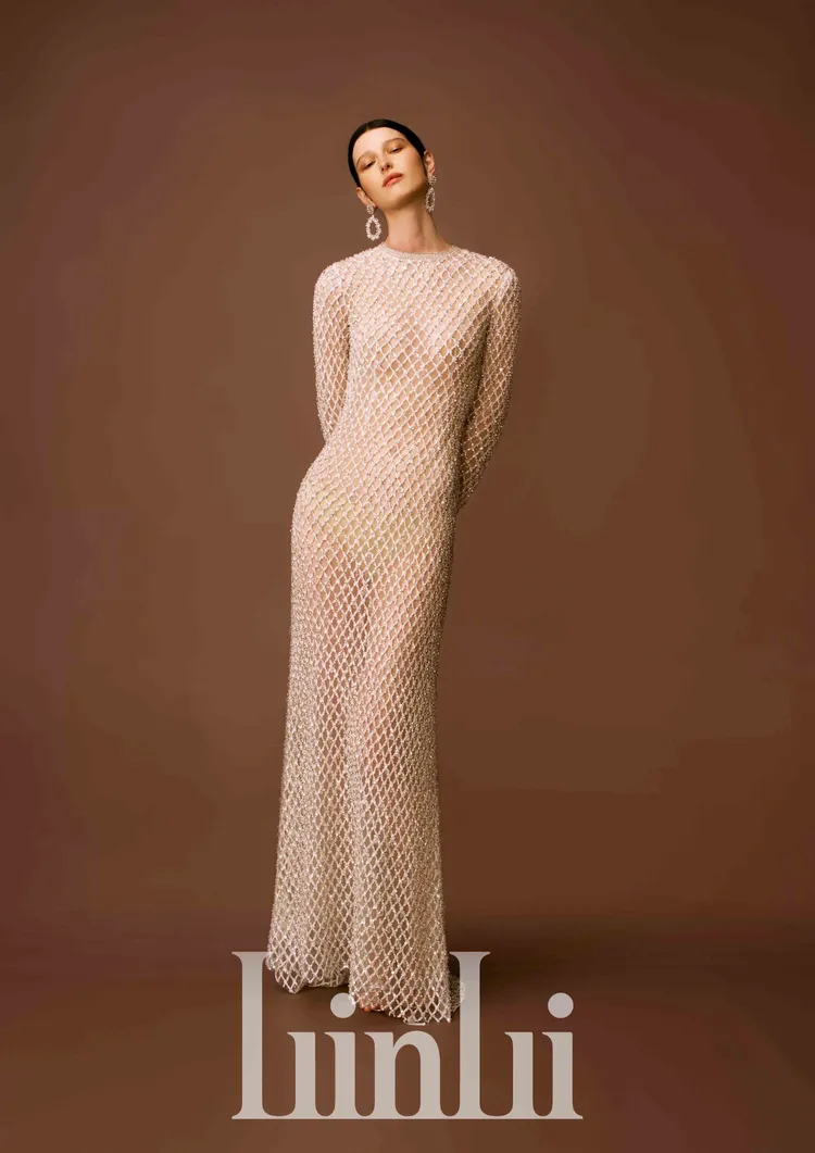 白標系列大網格星鑽直身長袖白紗，以銀白色窄襬H-Line輪廓呈現強烈時裝感線條，運用珠工縫製成大菱形網格圖騰，並在小圓領口及袖口以手工框邊，貴氣又時尚。品牌提供 