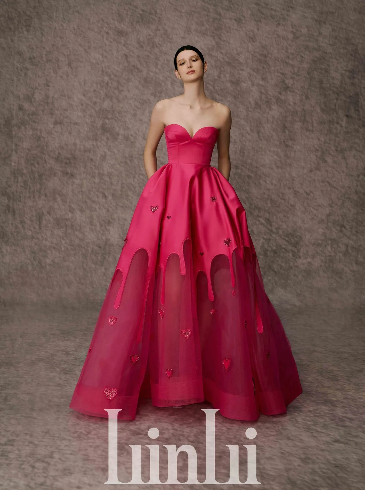 白标高订系列桃红爱心透视镂空礼服，将缎布和下半截透明硬网以贴布绣结合，手工珠绣爱心图腾点缀裙摆，并以蛋糕奶油浇淋的视觉效果增添年轻趣味气息，裙子上还做了时装感的口袋设计，别有率性风格。品牌提供 