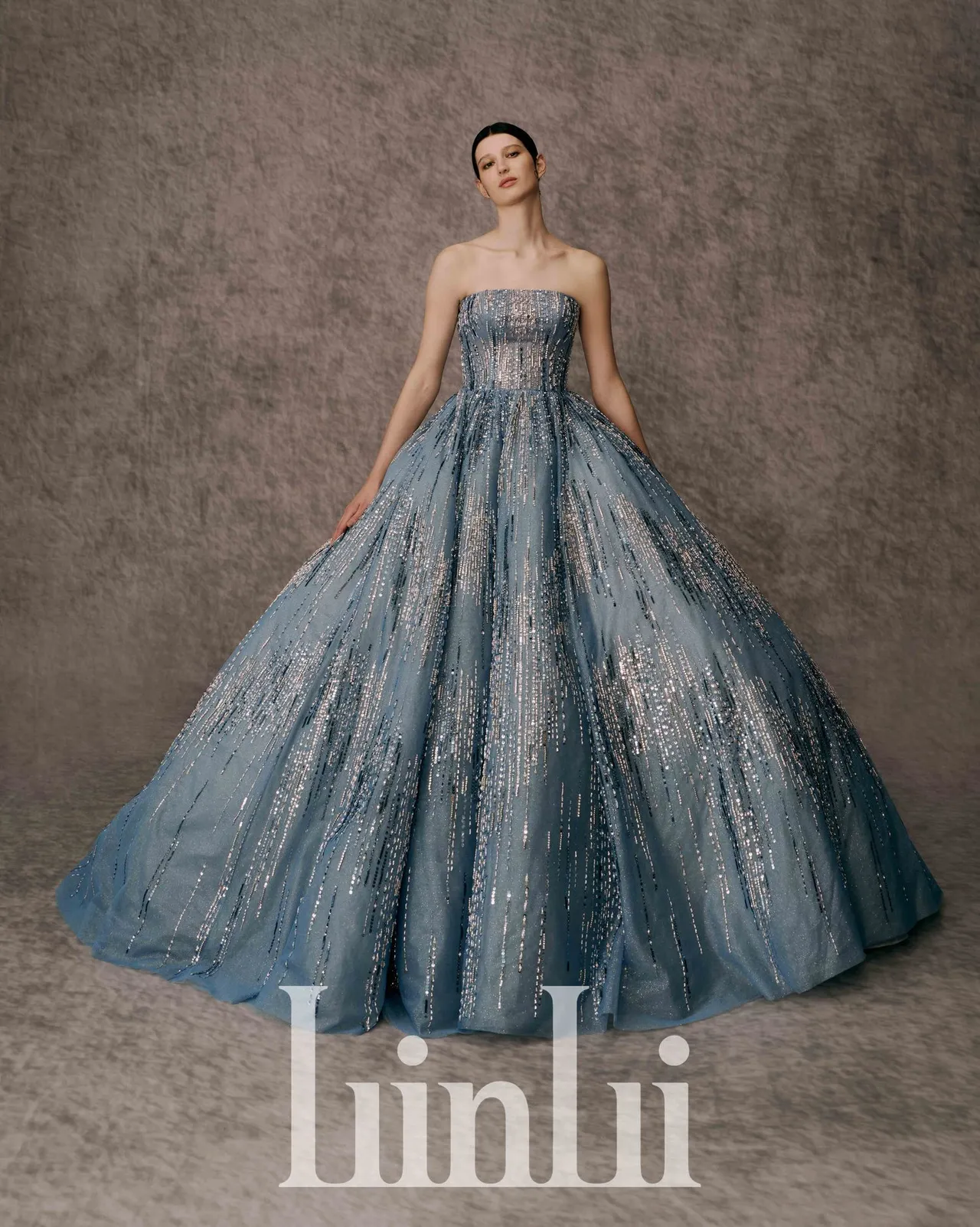 白标系列蓝烟火晚礼服，取用莫兰迪灰阶色系的蓝，并以蓝和灰网层叠做出层次裙摆设计，缀饰银色缝珠，就像在初夏的晴空夜里绽放的烟火。品牌提供