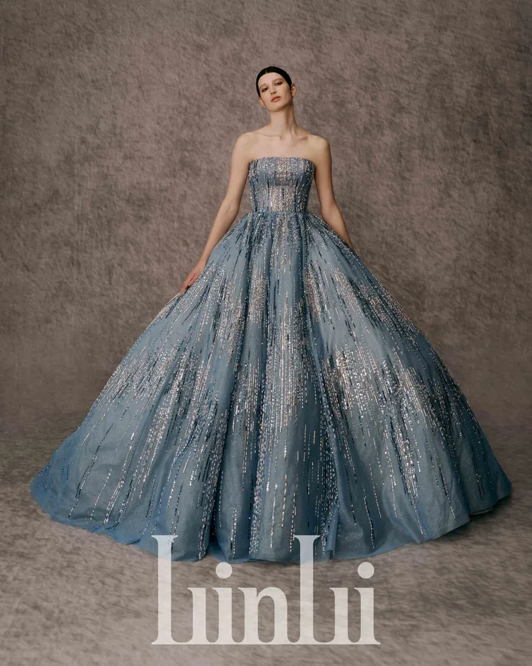 白標系列藍煙火晚禮服，取用莫蘭迪灰階色系的藍，並以藍和灰網層疊做出層次裙襬設計，綴飾銀色縫珠，就像在初夏的晴空夜裡綻放的煙火。品牌提供
