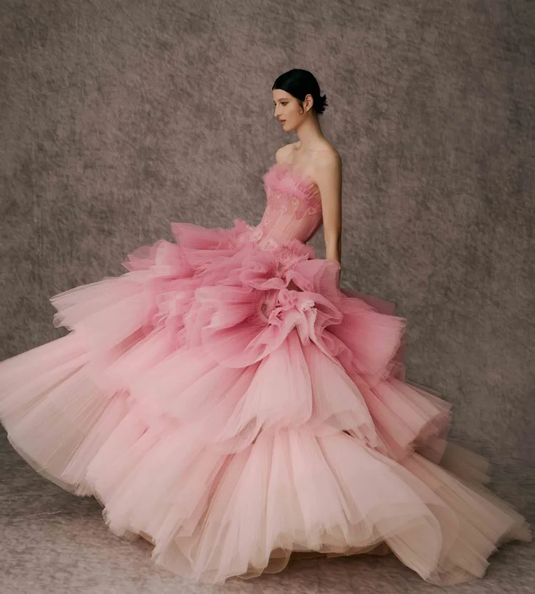 白標系列愛心粉色漸層晚禮服，由深漸淺的浪漫粉色創造視覺效果並能拉高身形比例，更像一朵綻放的大花 ，在透膚的細節處有不經意的出現甜美心形，巧妙呼應領口心形的細節，浪漫滿分。品牌提供 