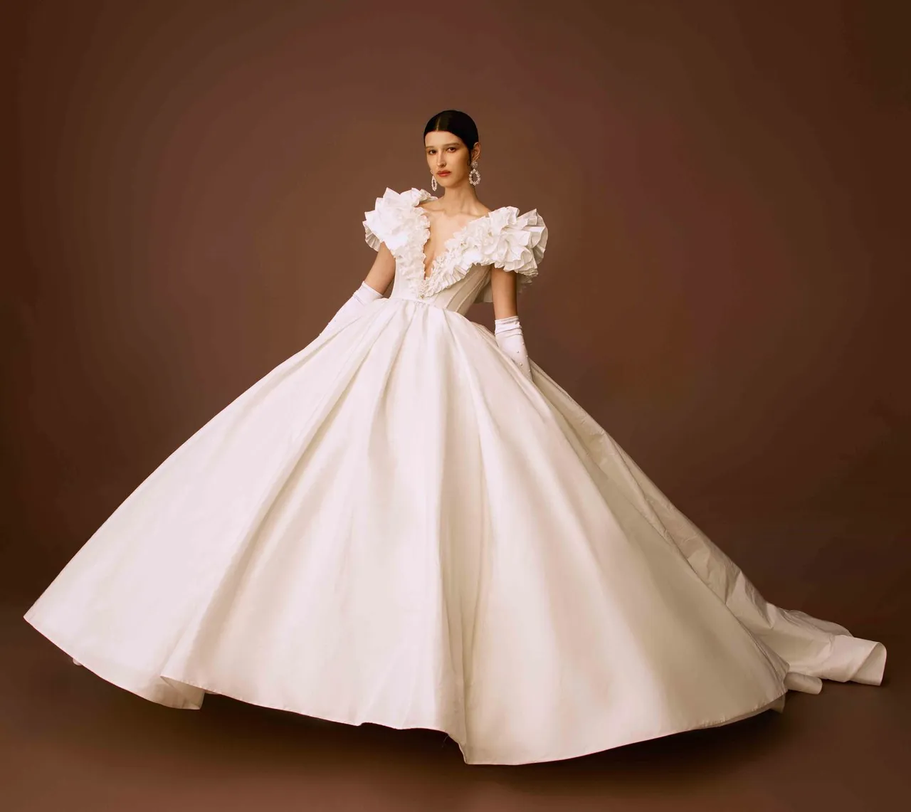 白标系列塔夫塔女皇荷叶领饰白纱充满公主气息，微落肩深V剪裁的义大利塔夫塔绸缎立体空气感荷叶缎面白纱，搭配特殊蝴蝶结变化型短头纱，复古又带点现代感。品牌提供