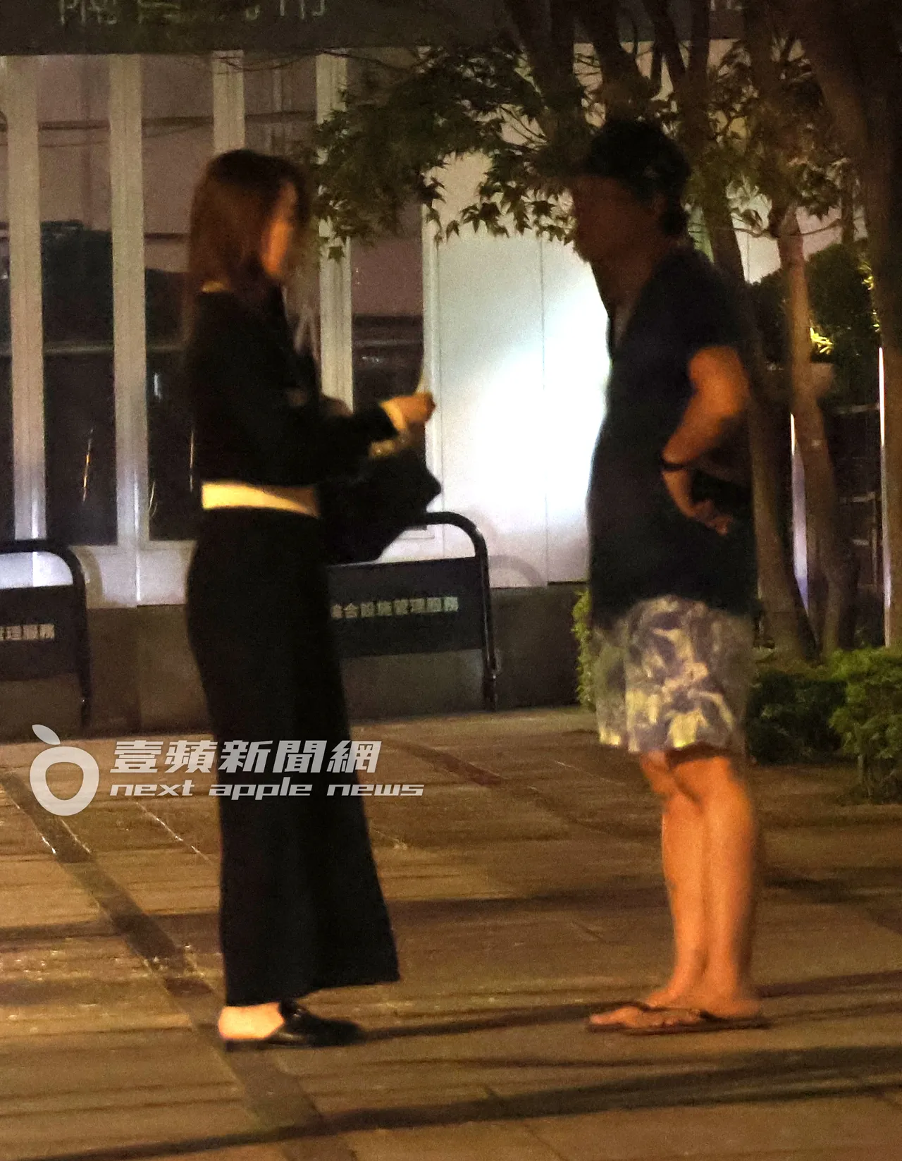周品均(左)和1名穿著休閒的男子在路邊聊天。特勤中心攝