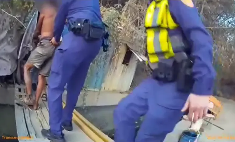 警員小心翼翼押解曾嫌走過木板橋。讀者提供