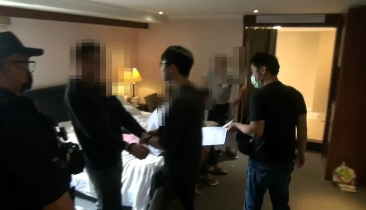 警方上銬逮捕詐騙集團成員。翻攝畫面