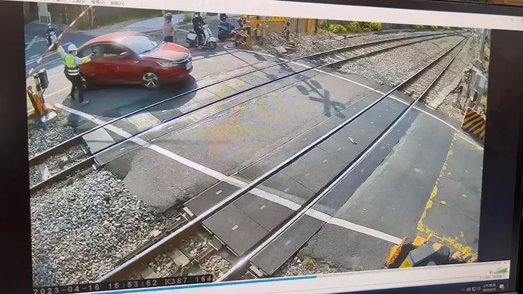 平交道保全員趕緊伸手將遮斷桿拉起，讓自小客車退後離開軌道。翻攝畫面