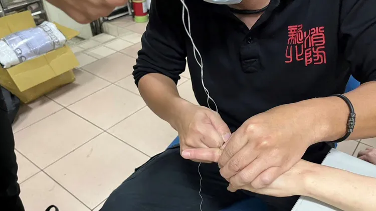 黃國峰以牙線纏繞王女手指。新北市消防局提供