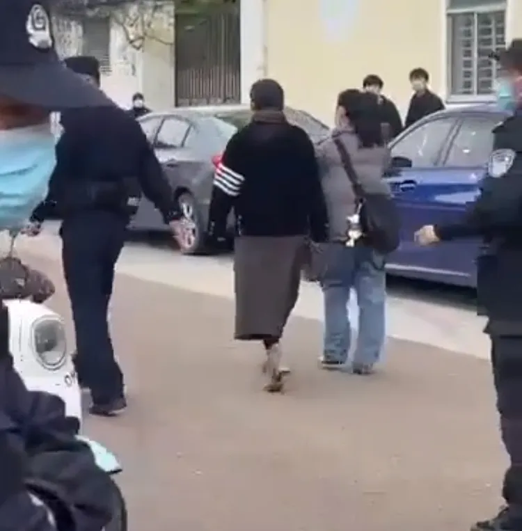 方女(灰衣斜背包者)在眾家長抗議下，灰溜溜走避。翻攝自互聯網