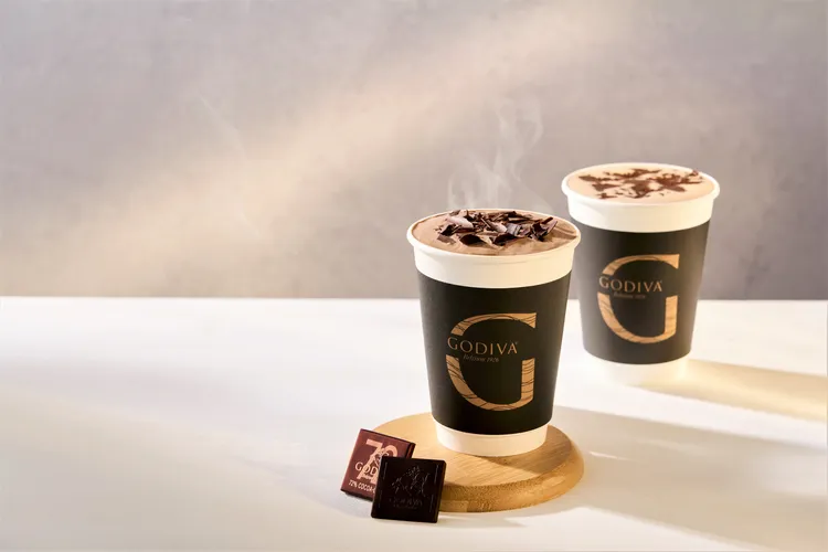 全系列四款可可特調飲品，頂部均勻點綴著GODIVA手工巧克力刨花卷片，不僅可品嚐可可的甘醇苦甜，入口即融的巧克力刨花卷片更為滿溢香氣的可可飲畫龍點睛。業者提供