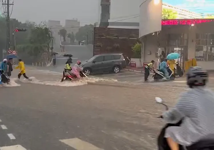弘光科大校門前水勢洶湧，校方人員協助學生脫機車。讀者提供