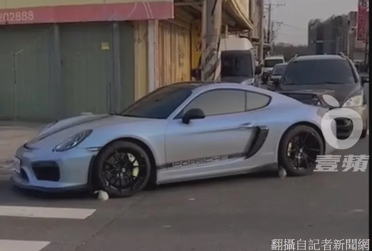 保時捷4個輪胎前後被放置瓜果，車主不願與水果攤阿北起衝突，卡在路口動彈不得。翻攝自記者新聞網