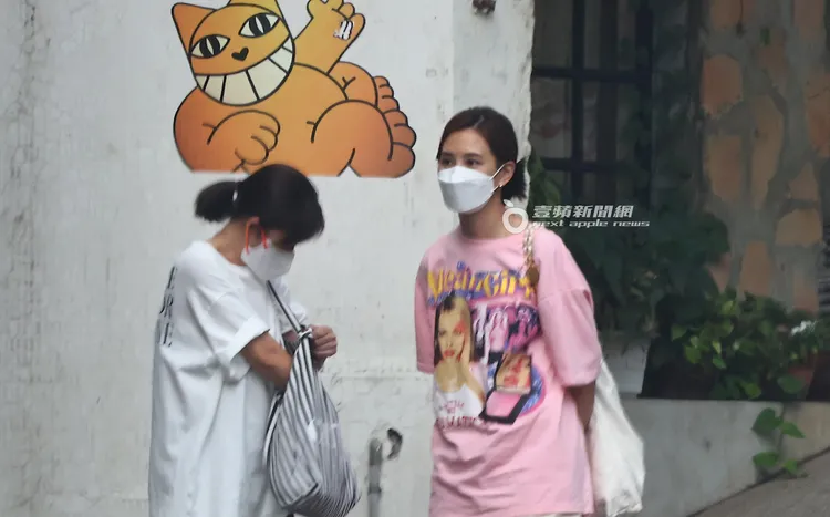 安心亞（右）駝著背，臉上面無表情的與友人站在街頭等待。特勤中心攝