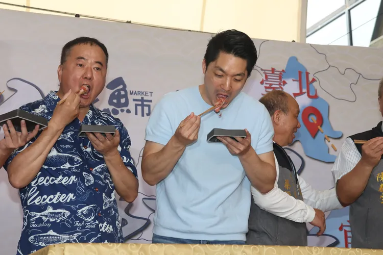 身為宜蘭女婿的台北市長蔣萬安（中）也大口吃起黑鮪魚生魚片。彭欣偉攝