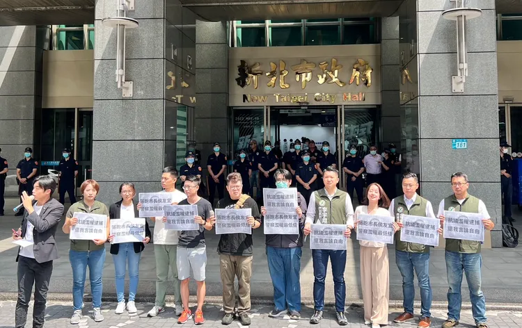 民團昨到新北市府門口舉牌抗議，並用強力水槍在地上留字諷刺落跑市長。翻攝畫面