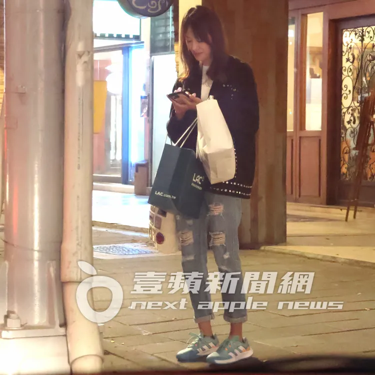 賈永婕等計程車邊看手機訊息，面帶笑容。特勤中心攝