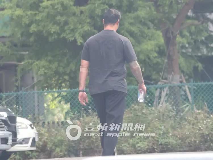 「國民大師兄」林智勝，手拿FIJI斐濟礦泉水，步出商辦大樓，左手還纏著止血繃帶。特勤中心攝