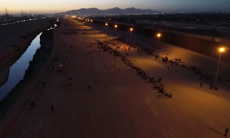 大量移民等在美國邊界的柵欄旁邊。美聯社