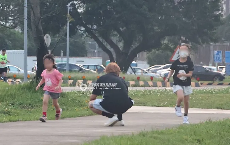 歐弟（中）蹲下身子拿起手機拍女兒們奔跑時的歡樂畫面。特勤中心攝