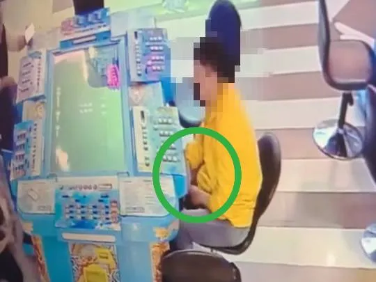 警方調閱監視器發現，男子以手提包遮掩，再伸手偷代幣。讀者提供