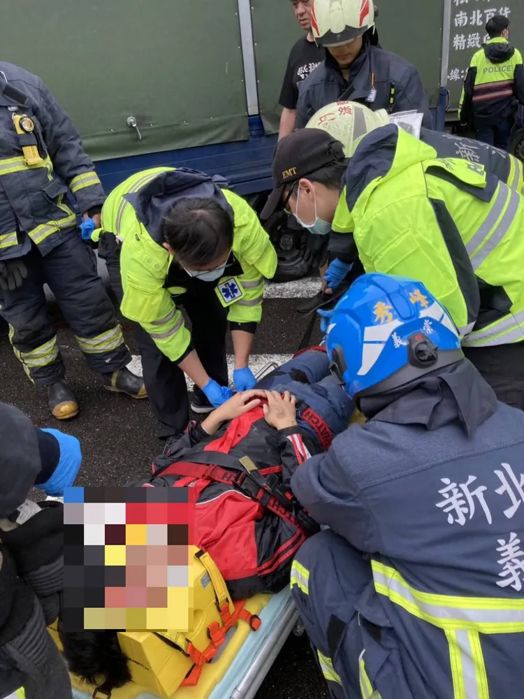 消防人員救出受困車底的機車騎士。翻攝畫面