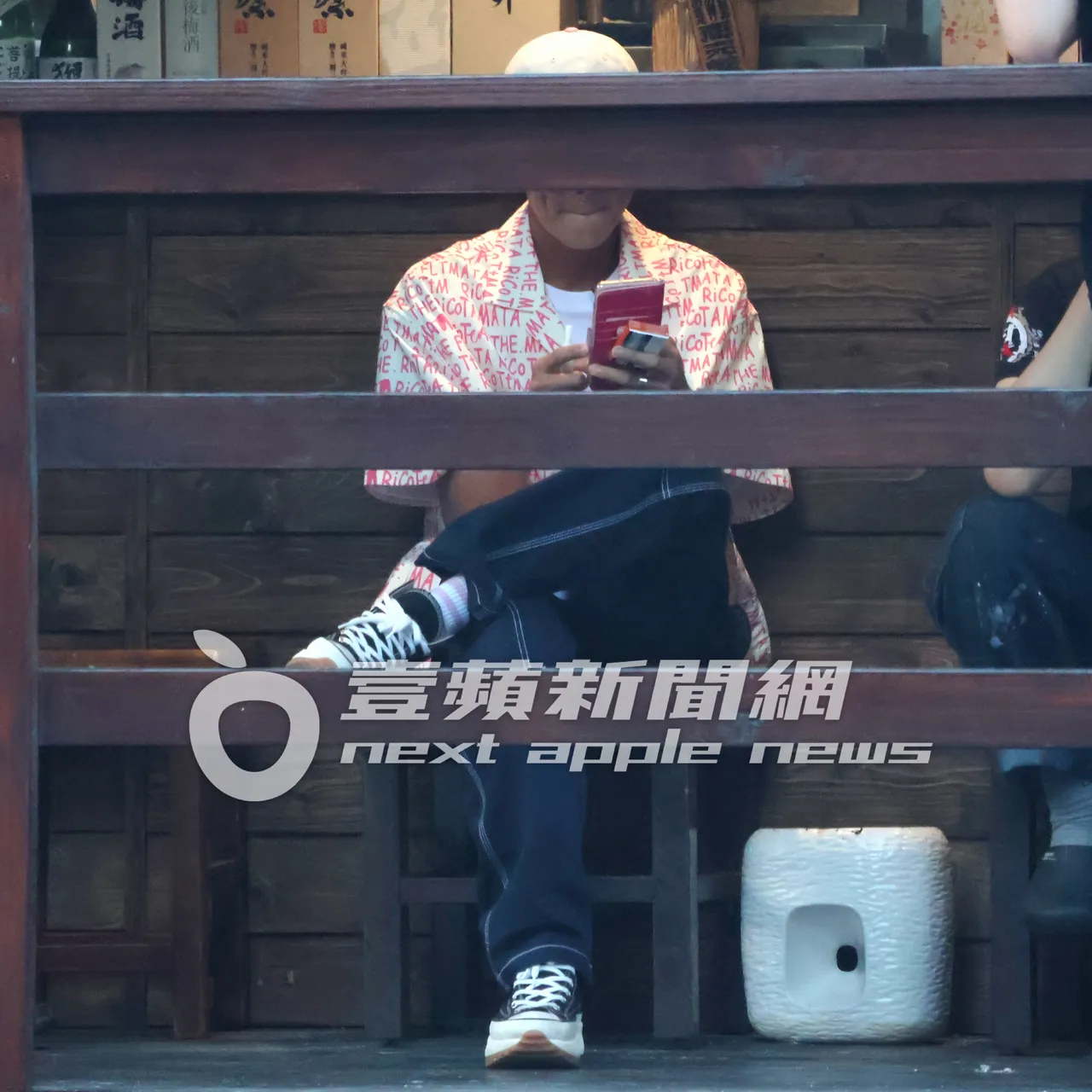 阿翔手拿加熱菸及菸盒邊滑手機。特勤中心攝