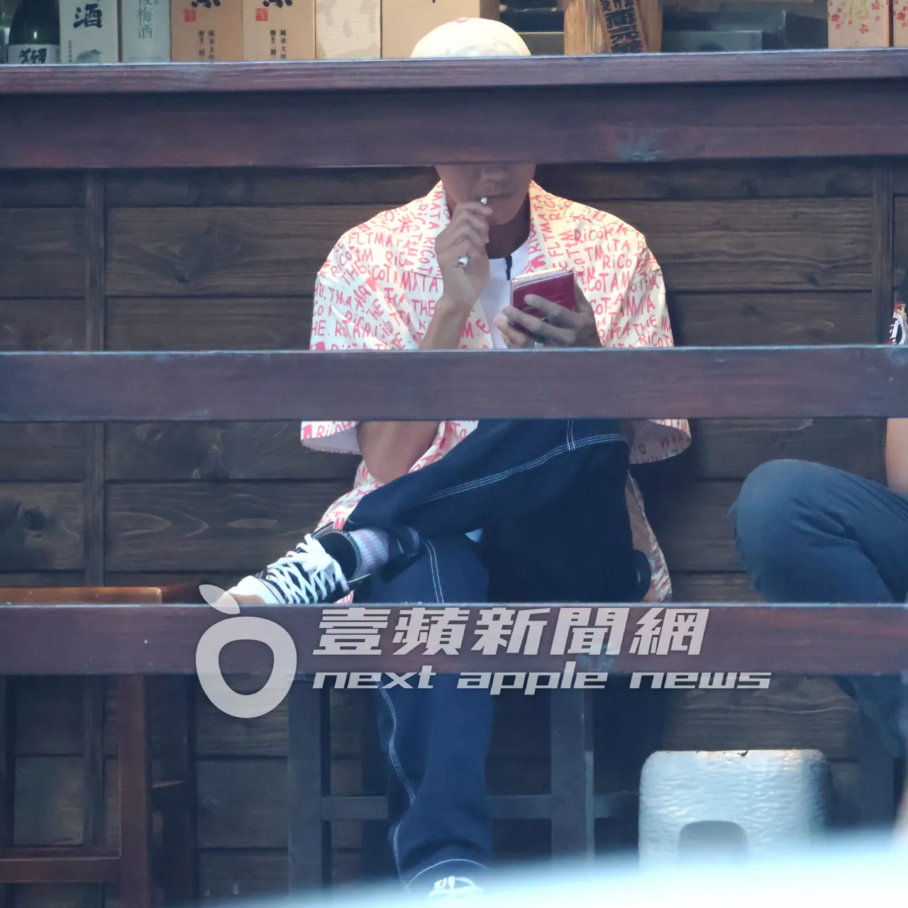 阿翔坐在室外拿起加熱菸吞雲吐霧滑手機。特勤中心攝