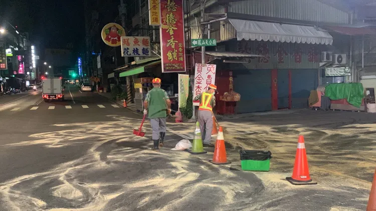 環保局人員在路面灑木屑吸附油漬。讀者提供