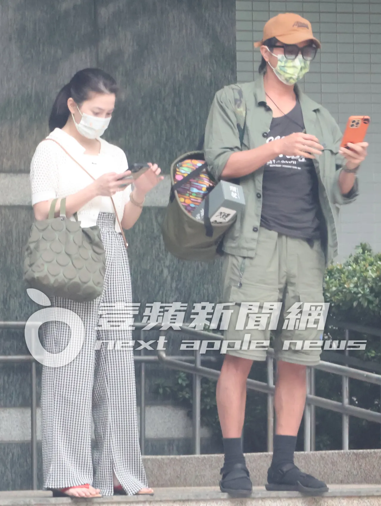 王少偉(右)與許藍方博士在家門口滑手機等計程車,準備外出。特勤中心攝