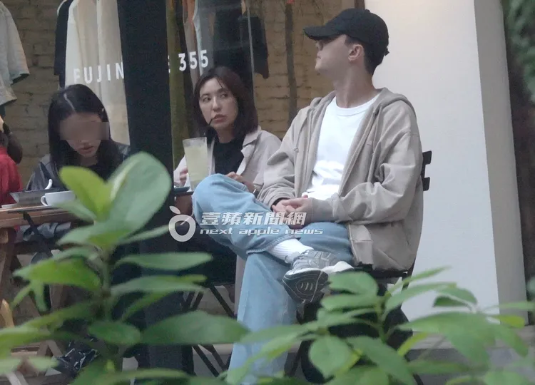 施柏宇（右）將帽子壓得相當低，坐在一旁耐心等待女友LinLin（中）處理公事。特勤中心攝