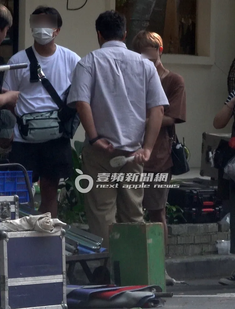 烈日炎炎，張孝全（中）拿起小電風扇掀開衣服往裡面通風散熱。特勤中心攝