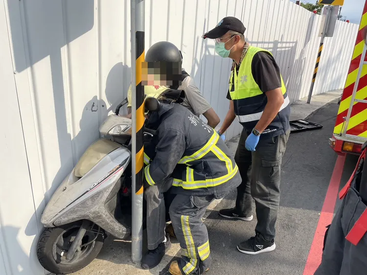 潘男連人帶車卡進告示牌桿與鐵皮圍籬中間。新北市消防局提供