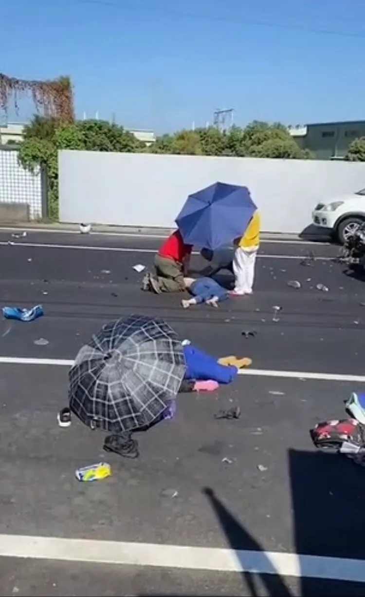 遭陳姓騎士撞倒的婦人，躺在路邊奄奄一息，在救護車抵達前，路人為她們撐傘。翻攝記者爆料網